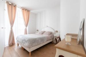 ein weißes Schlafzimmer mit einem Bett und einem Tisch in der Unterkunft Appartement Vintage Le Bon Marché - III in Paris