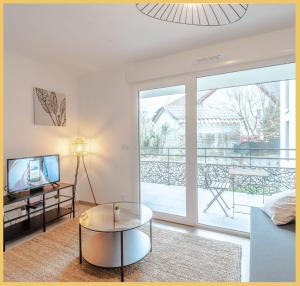 ein Wohnzimmer mit einem Couchtisch und einem Balkon in der Unterkunft Appartement T2 Sublime Beaumont in Beaumont