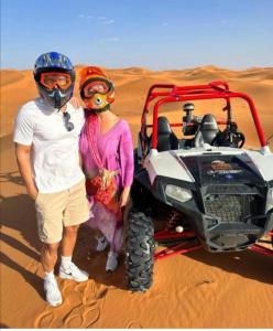 a man and a woman standing next to a atv in the desert at Standar camp merzouga in Merzouga