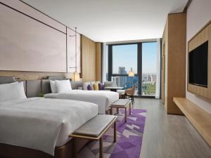 ein Hotelzimmer mit 3 Betten und einem TV in der Unterkunft JW Marriott Hotel Xi'an Southwest in Xi'an