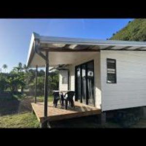 2 chaises assises sur une terrasse couverte d'une maison dans l'établissement Tiny House Moorea Haylee, à Papetoai