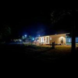 une maison la nuit avec des lumières devant elle dans l'établissement Tiny House Moorea Haylee, à Papetoai