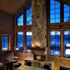 a living room with a stone fireplace and windows at Idre Mountain Lodge in Idre