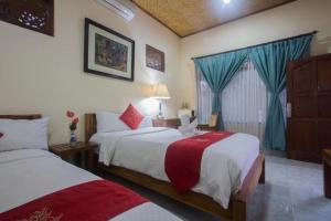 a hotel room with two beds and a window at Masna House in Ubud