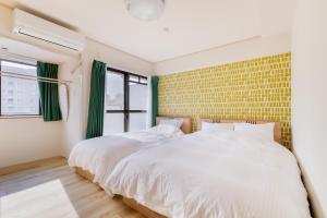 ein Schlafzimmer mit einem weißen Bett und einer gelben Ziegelwand in der Unterkunft グランシャーギ in Osaka