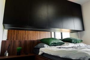 1 cama con cabecero negro y 2 almohadas verdes en Luxury Apartment KVP, en Myslava