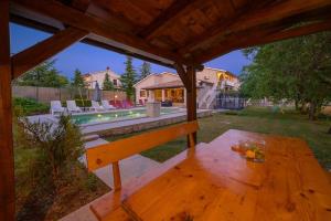 a wooden table in a backyard with a pool at Villa Rojnići 1 by IstriaLux in Orihi