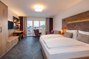 a hotel room with a large bed and a desk at Hotel Zehnerkar & Hotel Obertauern in Obertauern