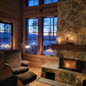 a living room with a stone fireplace and a chair at Idre Mountain Lodge in Idre