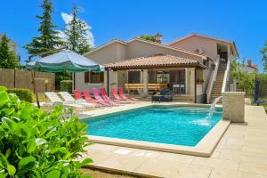 a swimming pool with chairs and an umbrella next to a house at Villa Rojnići 1 by IstriaLux in Orihi