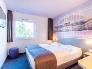 ein Hotelzimmer mit einem Bett und einem Gemälde an der Wand in der Unterkunft B&B Hotel Mannheim in Mannheim