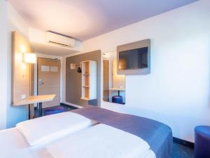 ein Hotelzimmer mit einem Bett und einem TV in der Unterkunft B&B Hotel Mannheim in Mannheim