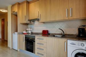 a kitchen with wooden cabinets and a sink and a dishwasher at Belair Tazacorte in Tazacorte