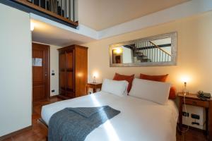 a bedroom with a white bed and a mirror at Locanda Delle Corse in Rome