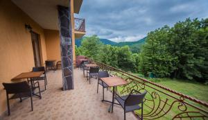 a balcony with tables and chairs and a view of the mountains at Vovk Gasthaus in Sinyak