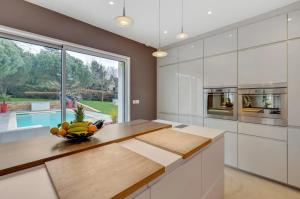 eine Küche mit weißen Schränken und einer Obstschale auf der Theke in der Unterkunft Olympic Games - Exclusive House in Villennes-sur-Seine