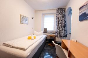 een kamer met 2 bedden, een bureau en een raam bij Pension Krone in Freiberg