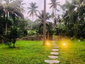 a path in the grass with two lights on it at Outskirts Of Heaven in Kamburugamuwa
