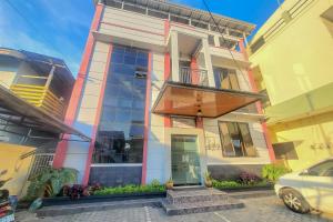 a building with a balcony and a car parked in front at RedDoorz near Wisma Cahaya Abadi Sepinggan Aiport in Balikpapan