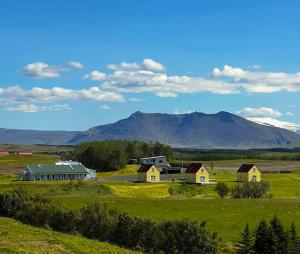 a group of houses in a field with mountains in the background at Hótel Lækur in Hella