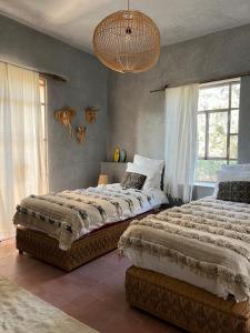 a bedroom with two beds and a chandelier at Dar Maha - Amazing villa - pool 15x5M can be heated in Essaouira
