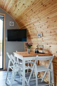 a dining room table with chairs and a flat screen tv at Little Quarry Glamping Bed and Breakfast in Tonbridge