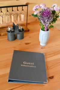 a book sitting on top of a table with a vase of flowers at Little Quarry Glamping Bed and Breakfast in Tonbridge