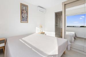 ein weißes Schlafzimmer mit einem weißen Bett und einem Fenster in der Unterkunft Villa vue mer proche du centre in La Croix-Valmer