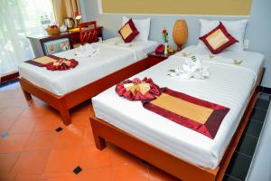 two beds in a hotel room with bows on them at Thai Hoa Mui Ne Resort in Mui Ne