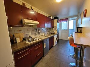 une cuisine avec des placards bruns et un comptoir dans l'établissement Charmante chambre chez l'habitant, à Ivry-sur-Seine