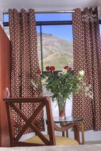 un jarrón de flores sentado en una mesa junto a una ventana en Siball Hotel, en Abancay