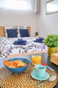 einen Tisch mit einer Schüssel Essen und einer Tasse Orangensaft in der Unterkunft Studio cosy, Wifi, Netflix in Fleury-Mérogis