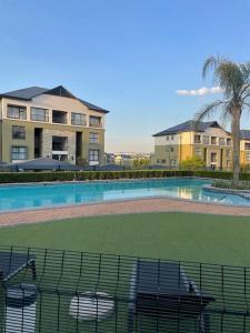 a swimming pool with chairs in front of a house at Apartment in Kikuyu, Waterfall in Midrand