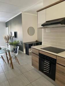a kitchen with a stove and a table in it at Apartment in Kikuyu, Waterfall in Midrand