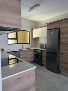 a kitchen with a black refrigerator and a dishwasher at Apartment in Kikuyu, Waterfall in Midrand