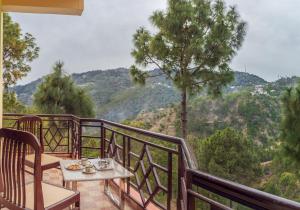 a table and chairs on a balcony with a view at Rudra Hotel And Resort ! New ! Mountain ! Kasauli in Kasauli