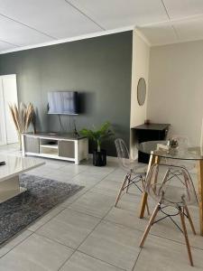 a living room with a tv and a table and chairs at Apartment in Kikuyu, Waterfall in Midrand
