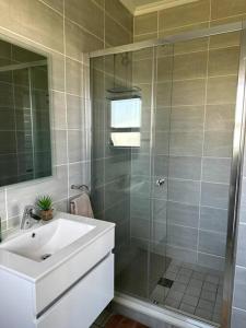 a bathroom with a glass shower and a sink at Apartment in Kikuyu, Waterfall in Midrand