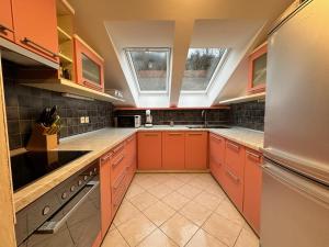 une grande cuisine avec des armoires orange et une lucarne dans l'établissement Apartment Izba Snovik, à Laze v Tuhinju