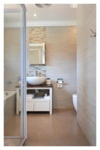 66 On Monzali 4 Star Luxury Guesthouse في هيلتون: حمام مع حوض أبيض ومرحاض