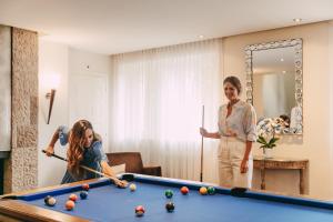 two women standing in a living room with a pool table at Château d'Ouchy in Lausanne