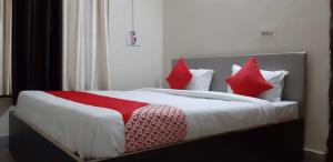 um quarto com uma cama com almofadas vermelhas e brancas em Hotel Bhubaneswar Pride em Bhubaneshwar