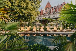 una piscina con sedie e ombrelloni di fronte a un edificio di Château d'Ouchy a Losanna