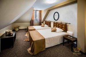 a bedroom with two beds and a mirror on the wall at Wellness Hotel Bulgaria in Bansko +25 photos