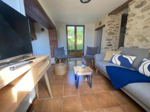 ein Wohnzimmer mit einem Sofa und einem Flachbild-TV in der Unterkunft Gîte de la Borderie in Saint-Silvain-sous-Toulx