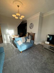 a living room with a blue couch and a clock on the wall at Lovely home with a river view in Mytholmroyd