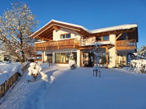 una casa cubierta de nieve con un patio en Wolke 8 en Bernau am Chiemsee