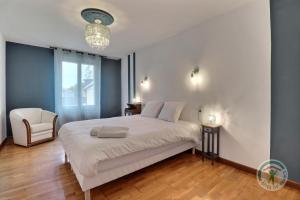 1 dormitorio con 1 cama blanca y 1 silla en Le karrdi, en Vitré