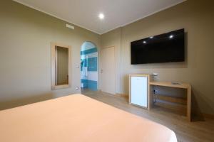 a bedroom with a bed and a television on the wall at Villaggio Stella del Sud & Resort in Pisciotta