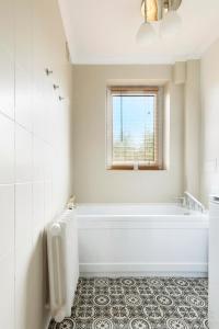 a white bathroom with a tub and a window at Elite Apartments Marine Brzeźno in Gdańsk
